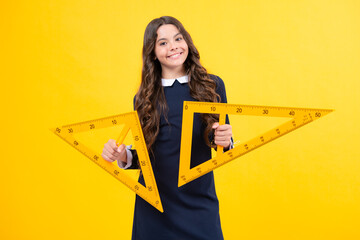Back to school. School girl hold ruler measuring isolated on yellow background.