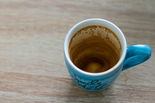 Taza de caf&eacute; bebido que te recuerda que sonr&iacute;as encima de una mesa de madera clara