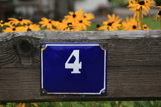 Nummer vier auf altem Emaille Schild befestigt an einem Holzzaun