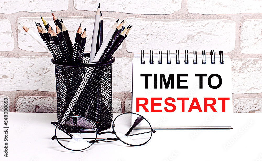 Poster a workplace in the house with glasses, pencils in a stand and a notebook with text time to restart o