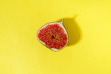 Juicy organic fig cut in half on a yellow background. Minimal summer concept flat lay