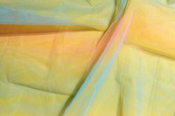 Yellow fabric background. Silk fabric in iridescent colors creates folds. Multicolored textiles. Texture