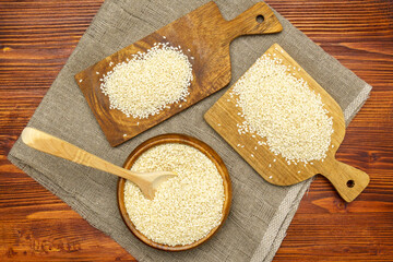 White sesame seeds in wooden bowl. Organic benne grains for healthy food, boosting immunity diet...