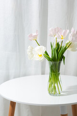 Light spring flowers in vase on white table