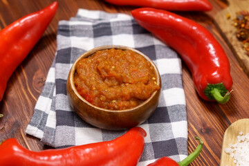 Ajvar from paprika, tomatoes, garlic and onions with spices on a brown wooden table. Balkan food. Selective focus