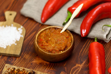 Ajvar from paprika, tomatoes, garlic and onions with spices on a brown wooden table. Balkan food. Selective focus