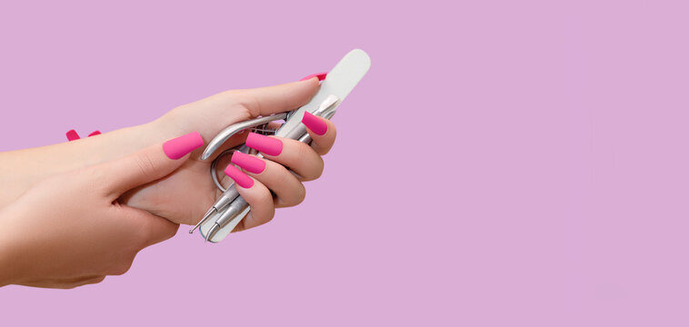 Female hand with pink nail design. Mate pink nail polish manicure. Female model hand hold manicure tools.