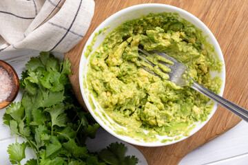 Mashed avocado in a bowl. Mexican guacamole, avocado sauce for toast. Table top view