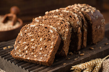 Rye bread with sunflower seeds sliced on wooden cutting board, closeup view