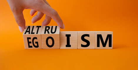 Altruism and Egoism symbol. Hand turns a cube and changes the word Egoism to Altruism. Beautiful orange background. Businessman hand. Business, psychological, Altruism and Egoism concept. Copy space