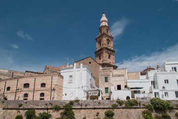 Campanario de la basílica Cattedrale Maria Santissima della Madia en Monopoli, Italia. El alto campanario con varias plantas destaca sobre el resto de edificios de la ciudad, foto en una mañana de ver