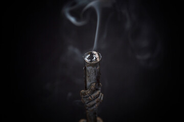 Old vintage black metal candlestick with smoke from an extinguished candle in the dark. Witchcraft...