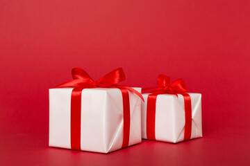 Gift boxes with red ribbon bow on color background