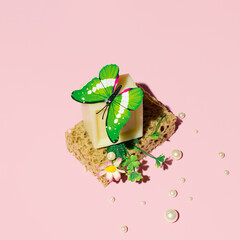 Handmade  eco friendly soap, shower sponge and butterfly, creative nature inspired beauty and care inspired layout against candy pink background. 