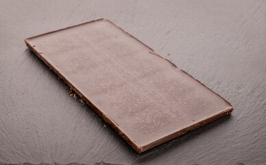 One bar of bitter dark chocolate on a slate stone, macro.