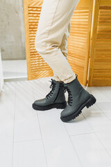 Fashionable women's stylish leather boots. Green women's genuine leather boots on feet close-up. New collection of winter shoes for stylish girls.