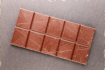 One bar of dark dark chocolate on a slate stone, macro, top view.