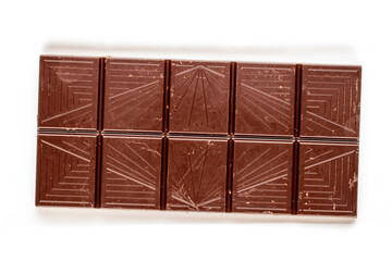 One bar of dark dark chocolate on a white ceramic plate, macro, top view.