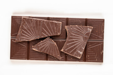 One bar of dark dark chocolate on a white ceramic plate, macro, top view.