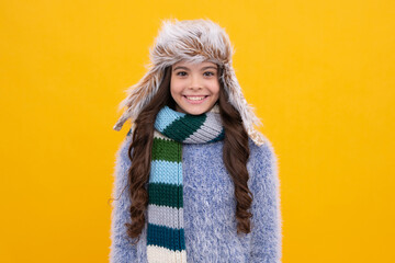 Teenager girl with winter hat over isolated yellow background. Winter christmas holidays, new year mood. Kids warm clothes. Happy face, positive and smiling emotions of teenager girl.