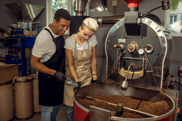 Fototapeta na wymiar Pleased roast masters monitoring the coffee roasting process
