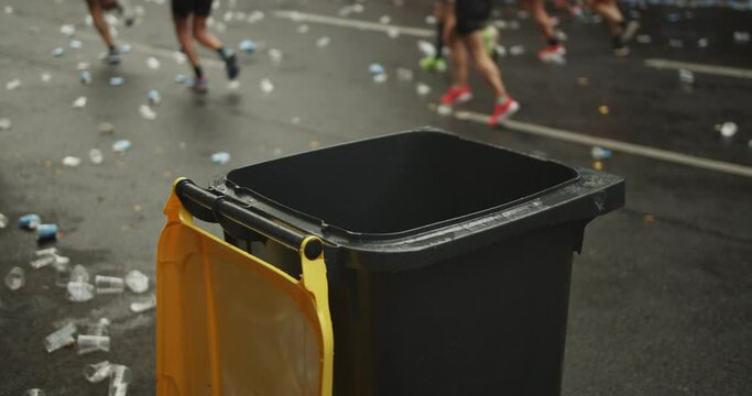 Close u of top of trash bin for rubbish at refreshment area on sport event. Athletes running on street around. Marathon run race, Berlin, Germany