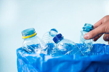 Man leaving a plastic bottle in a blue recycling bin
