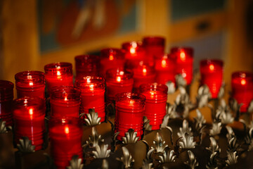 About twenty glowing red prayer candles in gold candle holders