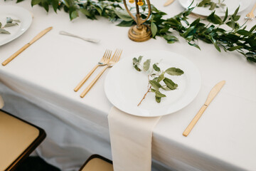 Elegant table set for a wedding meal with gold cutlery, white linen