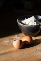 Ingredients for making dough - flour in a bowl, eggs. Hard light