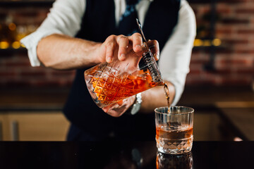 Bartender pours a cocktail into a glass