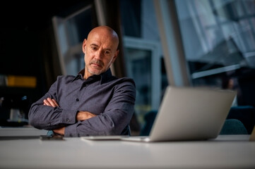 Shot of thinking business man using laptop while sitting at desk and working in a modern office....