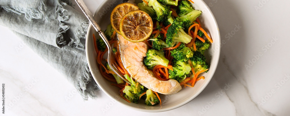 Wall mural a bowl of fried salmon with broccoli on a light marble table