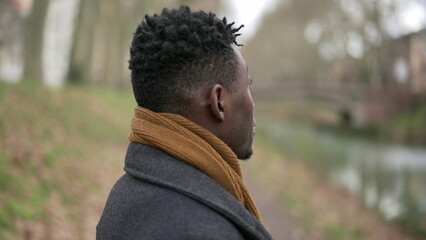 Pensive black man standing outside in cold winter season wearing scar and coat2