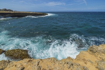 Fototapeta na wymiar Gorgeous view of big turquoise waves Atlantic ocean on western rocky coast of island of Aruba.