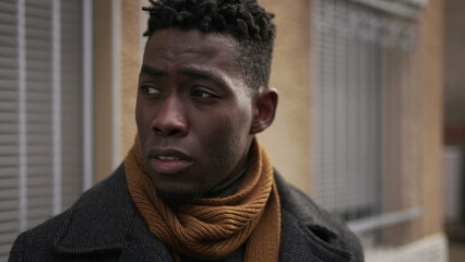 Pensive black man standing outside in city downtown. Thoughtful African guy waiting