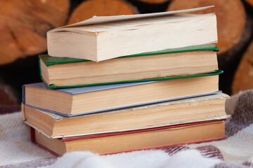 a close stack of old books on the woolen blanket  on wooden background in vintage style. Literature, education, hobby, reading and lifestyle
