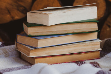 a close stack of old books on the woolen blanket  on wooden background in vintage style. Literature, education, hobby, reading and lifestyle. Knowledge and wisdom