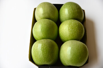 Six green apples on a cardboard backing on a white background. Delicious green apples close-up.