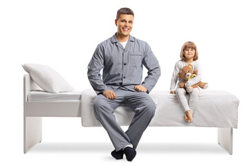 Young man and a little girl in pajamas sitting on a bed