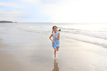 Cheerful Asian young girl child having fun running on tropical sand beach