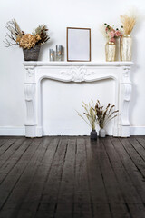 legant home interior in white tones under fireplace decorated with beautiful dried flower comosition. There are golden vases with dry flowers.