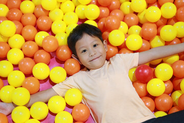 Fototapeta na wymiar Happy Asian child playing at colorful plastic balls playground.
