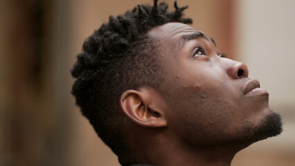 Obraz premium Pensive black African man standing outdoors thinking, looking up at sky in contemplation2