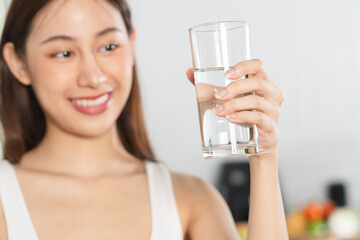 Happy beautiful, asian young woman, girl drinking, sip fresh glass of water for hydrate, holding transparent glass in her hand, thirsty at home. Health care, healthy lifestyle concept.