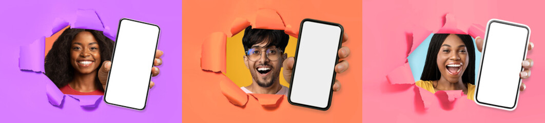 Three cheerful youngsters showing smartphones through hole in paper wall