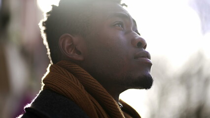 Pensive black African man standing outdoors contemplating life and spiritual path looking up at sky
