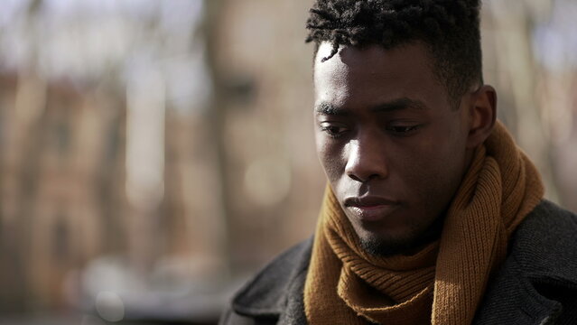 Pensive black African male walking outside in city while daydreaming alone