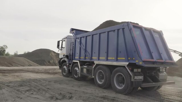 Mining dump truck working at the sand quarry. Scene. Industrial background at the quarry or at the construction site.