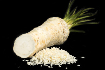 Horseradish root and grated horseradish on a black background closeup. Organic food, herb, spice,...